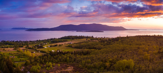 Naklejka na ściany i meble Dramatic Aerial Sunset View of Orcas Island, Washington. Drone aerial shot of Orcas Island located in the San Juan Islands and surrounded by the Salish Sea. Viewed from Lummi Island in the foreground.