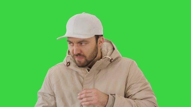 Man in winter outfit walking and coughing on a Green Screen, Chroma Key.