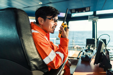 Filipino deck Officer on bridge of vessel or ship wearing coverall during navigaton watch at sea ....