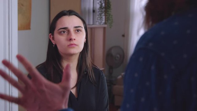 A young caucasian woman looks pathetic as his girlfriend berates her