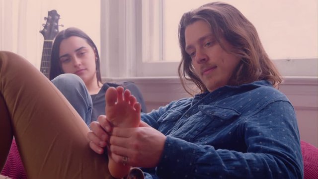 Close up - A young caucasian man massages his girlfriend's feet
