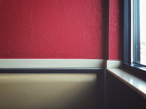 Sofa By Window Against Red Wall At Home