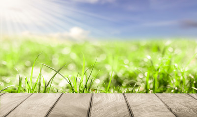 Empty wood on green grass with bokeh light and blue sky background