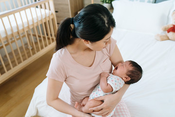 high angle view of first-time mom cuddling her baby daughter and trying to soothe her. infant...