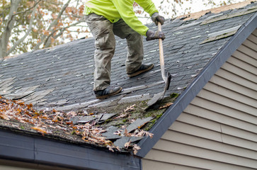 Man on a roof top removes old shingles