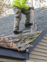 Worker removes shingles from an old roof