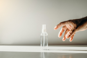 Asian man hand reaching for a spray bottle of alcohol. Concept about coronavirus.