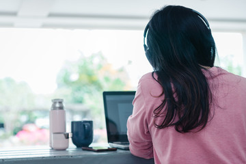 Portrait of a young Asian female adult learner studying online at home during Coronavirus or...
