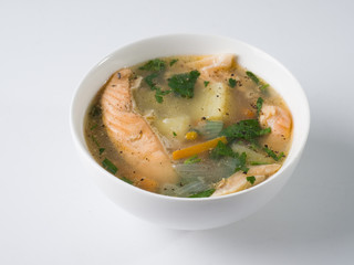 Fish soup in a white bowl. Salmon with potatoes and herbs. Side view