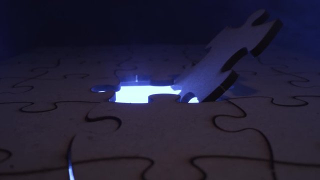 Jigsaw puzzle piece missing with light flashing through the open hole - symbolic element for Autism, business, problem solving, mystery and crime
