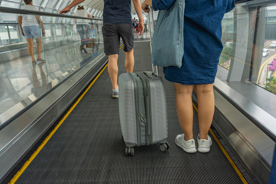 Rearview of travelers standing on moving walkway at the airport