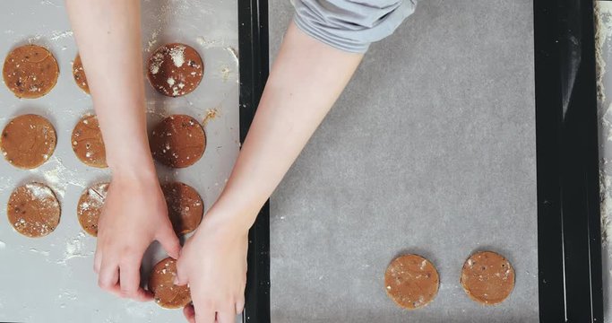 Female hands spread the cookie dough on a baking sheet covered with baking paper.