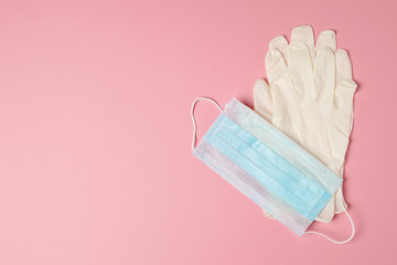 Medical face mask and pair of latex medical gloves isolated on pink background, coronavirus and infection protection.