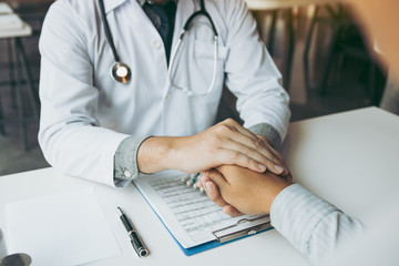 Doctor is holding the patient's hand and giving hope about treating the symptoms of the disease.