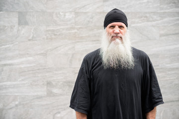 Mature handsome bearded hipster man against concrete wall