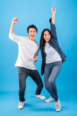 Excited young Asian couple man and woman happy celebrate success over blue background, winner...