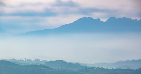 Fototapeta na wymiar Mountain range with visible silhouettes through the morning colorful fog.