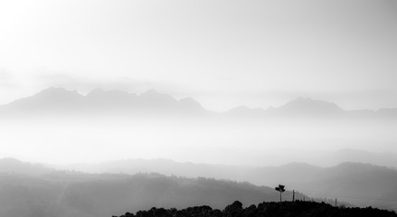 Mountain range with visible silhouettes through the morning colorful fog.