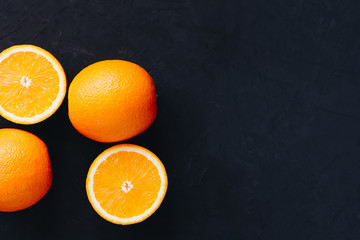 Halves and slices of fresh juicy oranges on black textured background. - 344045019