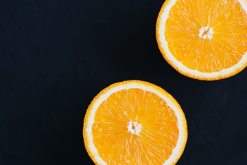 Top view on orange slices on black background.