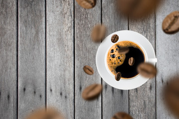 Top view of brown roasted coffee beans falling and flying to coffee cup.Represent breakfast for energy and freshness concept.