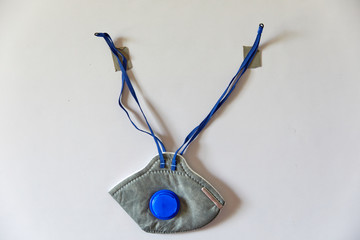 Gray FFP1 mask hanging on a white wall with double sided tape (Horizontal 35mm aspect ratio). Used...