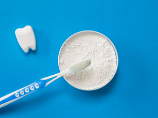 Figure of a healthy tooth and a brush with tooth powder on a blue background.