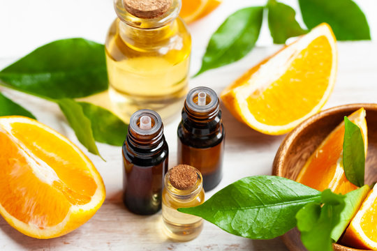 Concept of natural organic orange essential oil for skin face and body health care. Moisturizing, aromatherapy, detox treatment, anti-stress effect. Fresh fruit, green leaves, white background
