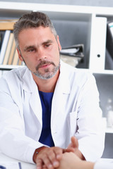 Fototapeta premium Friendly male doctor hold female arm in office during reception portrait. Examination result positive test calm down promise and cheer up grief and suffer treatment condolence ethics concept
