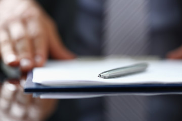Male arm in suit offer contract form on clipboard pad and silver pen to sign closeup. Strike a...