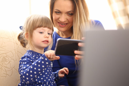 Cute little girl on floor carpet with mom use cellphone calling dad portrait. Life style apps social web network wireless ip telephony concept