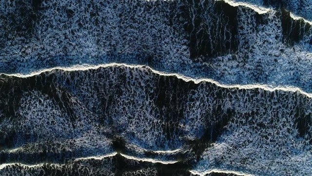 Aerial view of ocean waves in continuous repetition. Dark blue sea waves shot from above