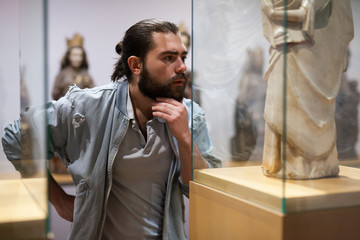 Man visiting sculpture hall in historical museum and looking at exhibits