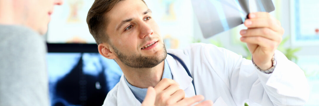 Portrait of doctor examining radiogram picture. Smiling physician pleased with results of treatment. Medicine and health care concept. Blurred background