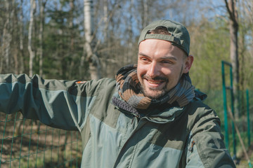 Obraz premium Smiling handsome gardener working in backyard. Portrait of man landscaping and taking care of his yard on a sunny day. 