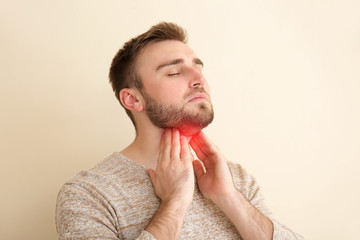 Young man checking thyroid gland on color background