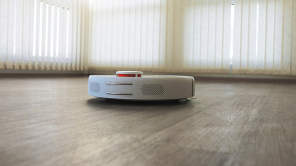 White robotic vacuum cleaner on linoleum wood floor smart cleaning technology