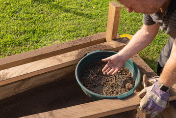 Sifting soil through a garden sieve to remove rubbish
