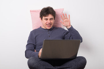 Man in pajamas is sitting at a laptop. Positive man at a remote work at home.