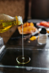 girl pours olive oil in a glass pan on a black table