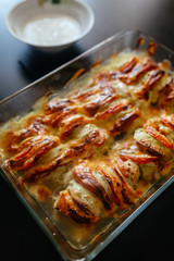 ready-made chicken with cheese and tomatoes stands in a baking sheet on a burning table
