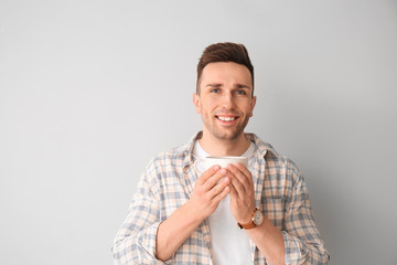 Young man drinking coffee on light background