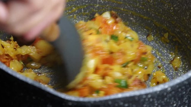 Frying Onions with Tomatoes, green chilies, garlic, ginger and cumin seeds to make Tadka to make of spicy Indian lentils called Daal tadka. A 4K video resolution.