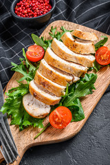 Fototapeta na wymiar Fresh salad with grilled chicken breast, arugula and tomato. Black background. Top view