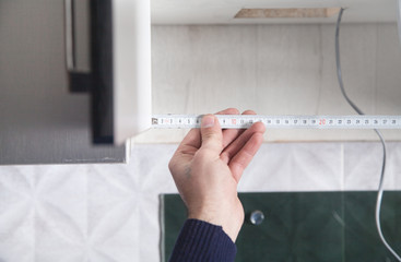 Man taking measures of a new kitchen cabinet.