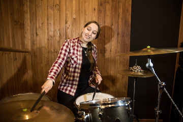 Professional drum set closeup. Beautiful young girl drummer in checkered shirt with drumsticks...
