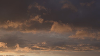 Beautiful evening blue sky at sunset with flaming bright light clouds. A warm summer evening at sunset.