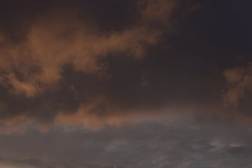 Beautiful evening blue sky at sunset with flaming bright light clouds. A warm summer evening at sunset.