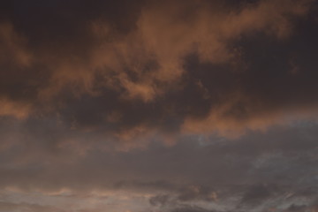 Obraz premium Beautiful evening blue sky at sunset with flaming bright light clouds. A warm summer evening at sunset.