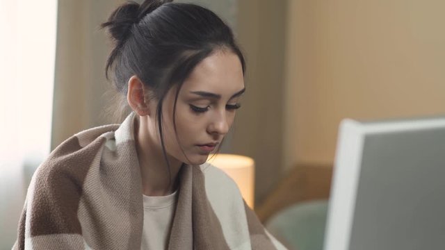 Young couple in quarantine, working at home, female manager working at a computer and checks documents, man uses a screen tablet and talking a mobile phone, makes noise and interferes with the girl's